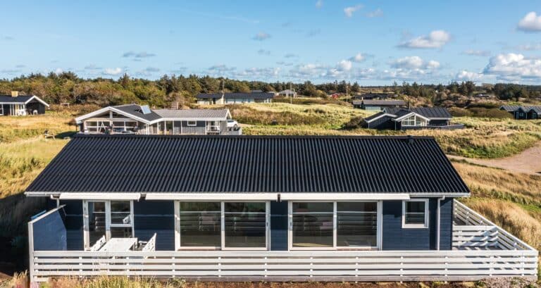 Sommerhus med sort tag og hvid terrasse set fra oven